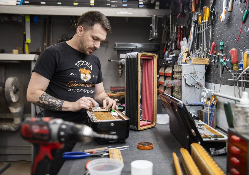 Gabe Hall-Rodrigues works on the inside of an accordion at the Petosa Accordions store in Lynnwood. (Olivia Vanni / The Herald)