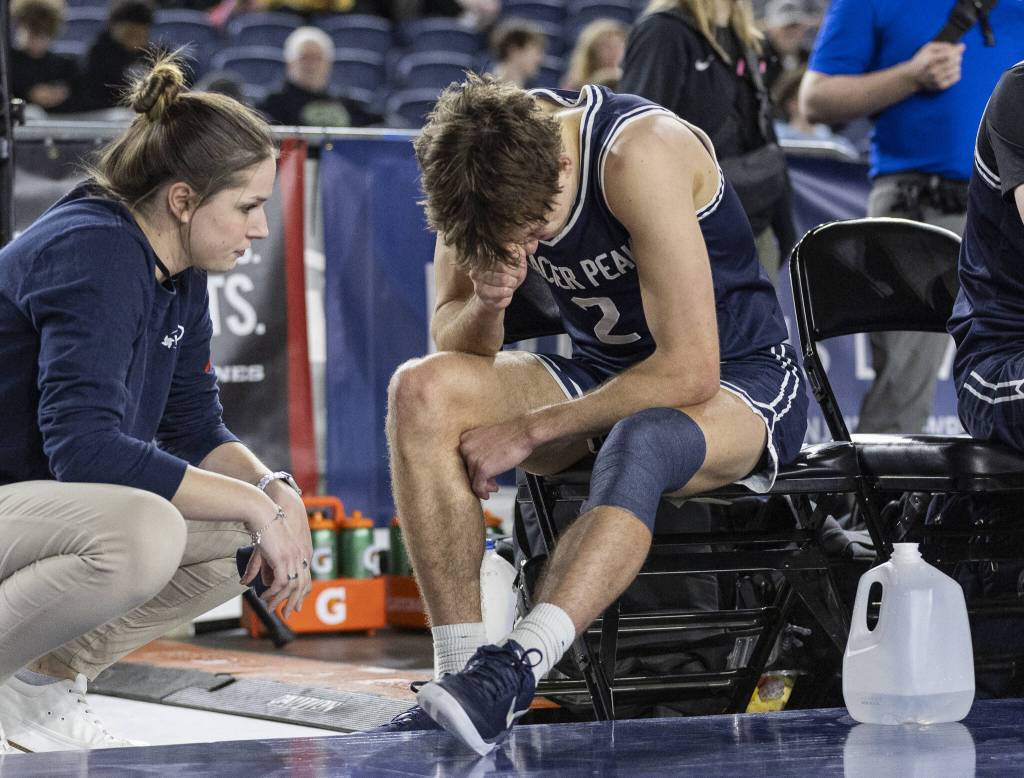 Glacier Peaks Jo Lee gets his legged wrapped before the start of overtime during the 4A boys quarterfinal game against Camas on Thursday, March 6, 2025 in Tacoma, Washington. (Olivia Vanni / The Herald)