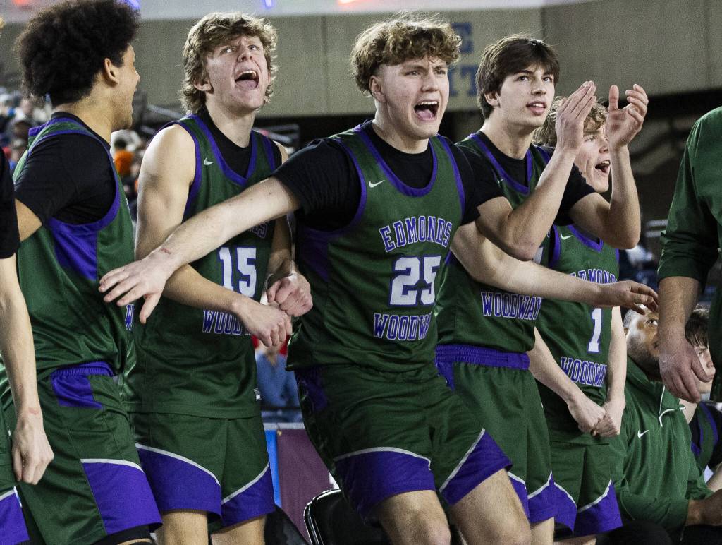 The Edmonds-Woodway bench reacts to a three-point shot during the 3A boys semifinal game against Mt. Spokane on Friday, March 7, 2025 in Tacoma, Washington. (Olivia Vanni / The Herald)
