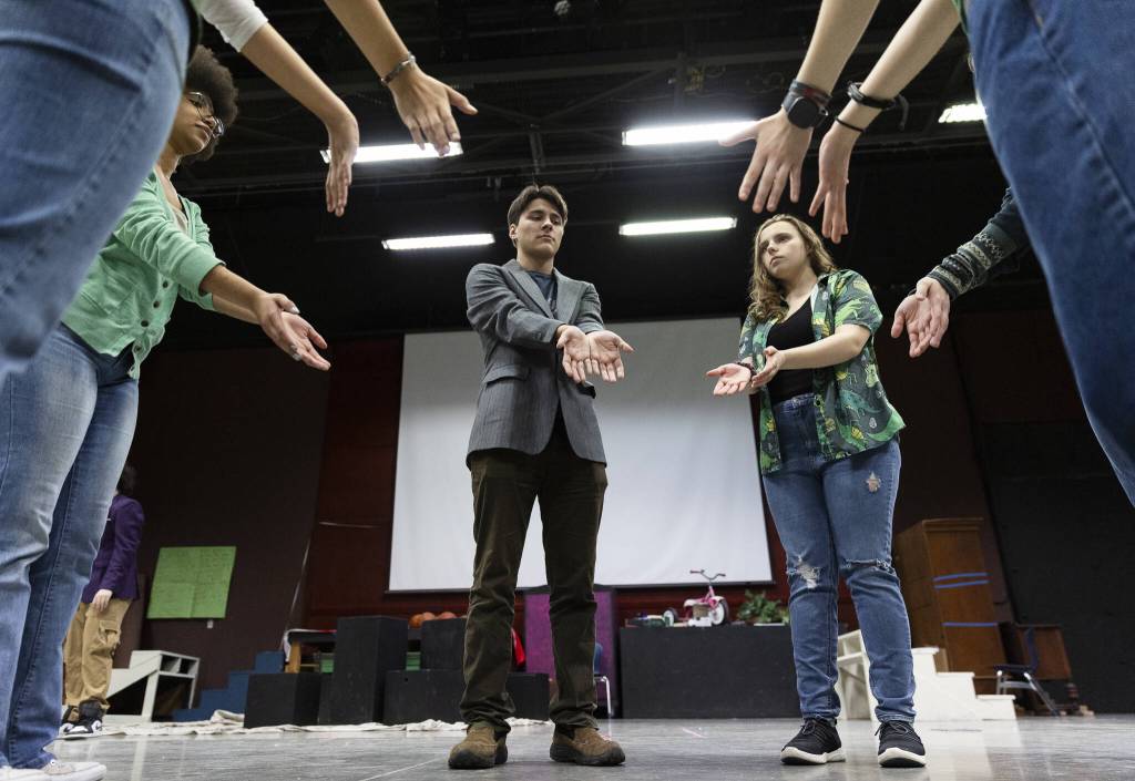 Tyler Pennington, left, Audria Cox, right and other actors do a quick exercise before they start a full run-through of their play at rehearsal on Monday, March 17, 2025, at Meadowdale High School in Lynnwood, Washington. (Olivia Vanni / The Herald)