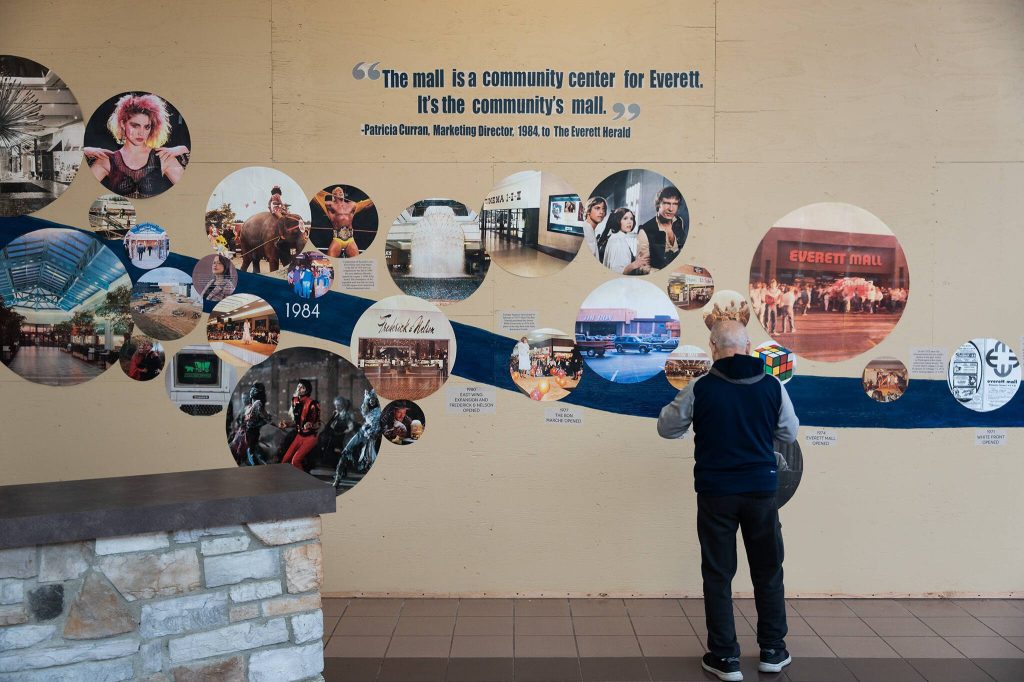 A shopper uses his phone to get a photo of a timeline mural that traces the history of the 51-year-old indoor mall that was once considered the premier place to go shopping in the city Monday, March 17, 2025, in Everett, Washington. (Will Geschke / The Herald)