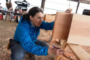 Elaina Jorgensen measures a tenon while volunteering with the Timber Framers Guild on Wednesday, March 19 in Monroe, Washington. (Will Geschke / The Herald)