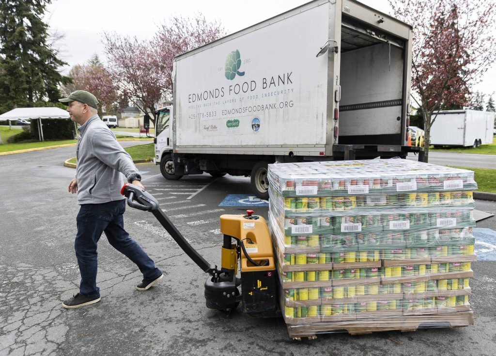 Scott McCormick unloads canned fruits and vegetables from the Edmonds Food Bank truck on Wednesday, March 26, 2025 in Edmonds, Washington. (Olivia Vanni / The Herald)