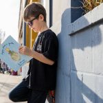 Oliver Popa, 7, poses with his book, "Drippey Plants a Garden," on Tuesday, March 25, 2025 in Edmonds, Washington. (Olivia Vanni / The Herald)
