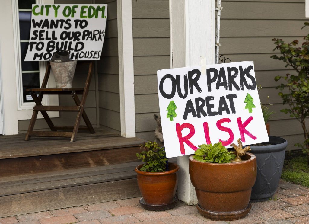 Signs against the potential comprehensive plan amendment to sell Hummingbird Hill Park are visible on the steps of a home neighboring the park on Monday, March 31, 2025, in Edmonds, Washington. (Olivia Vanni / The Herald)