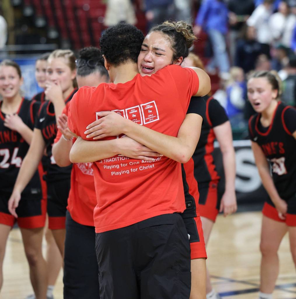 Kaleo Anderson hugs King's girls basketball head coach Dan Taylor after hitting a game-winner against Lynden Christian in a March 7, 2025 1A state semi-final game at the Yakima Valley SunDome. (Courtesy of King's Athletics / Donna Beard)