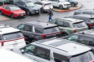 A person walks through the lot at Kia of Everett shopping for a car on Tuesday, April 1, 2025 in Everett, Washington. (Olivia Vanni / The Herald)