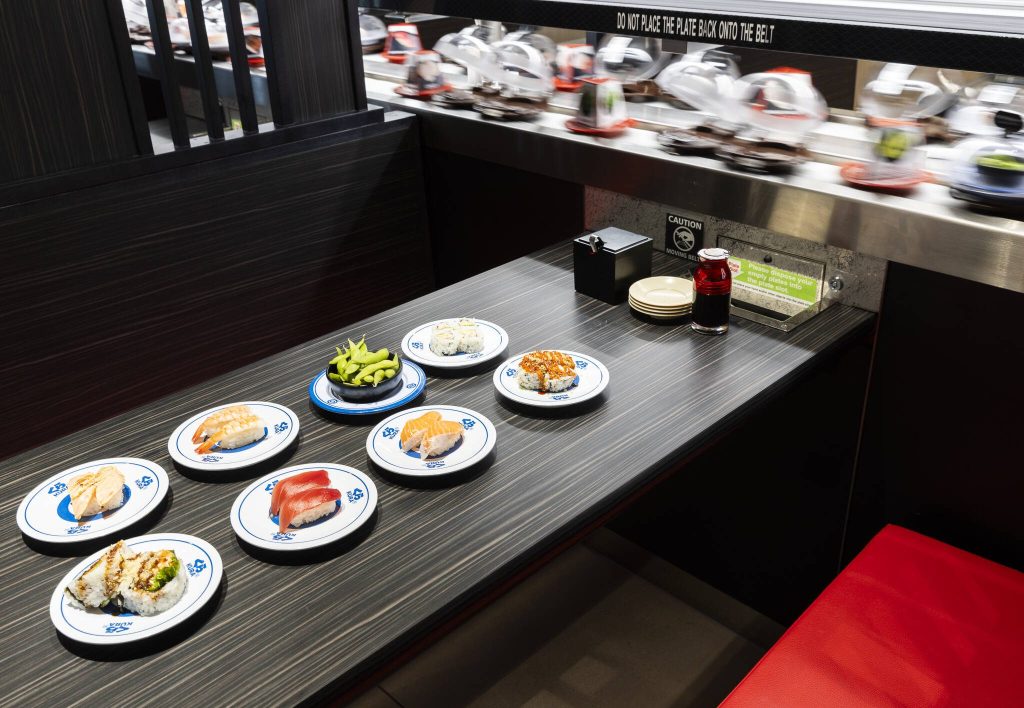 The conveyor belt moves past a table with a selection of food options available at Kura Revolving Sushi Bar on Monday, April 7, 2025 in Lynnwood, Washington. (Olivia Vanni / The Herald)