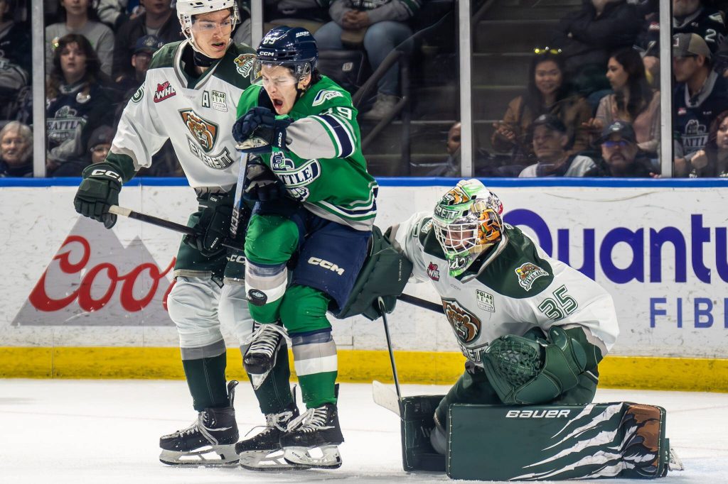 Seattle Thunderbirds forward Antonio Martorana absorbs a puck on his shin while screening Everett Silvertips goalie Raiden LeGall next to Silvertips defenseman Eric Jamieson during Everett's 1-0 double overtime win against Seattle in Game 6 of the WHL Playoffs First Round at accesso ShoWare Center in Kent, Washington on April 7, 2025. (Photo Courtesy: Dexter Guiang / Come as You Are Hockey)