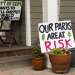 Signs against the proposed sale of Hummingbird Hill Park are visible on the steps of a home neighboring the park on Monday, March 31, 2025 in Edmonds, Washington. (Olivia Vanni / The Herald)