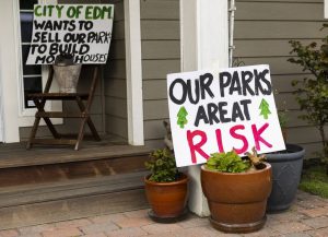 Signs against the proposed sale of Hummingbird Hill Park are visible on the steps of a home neighboring the park on Monday, March 31, 2025 in Edmonds, Washington. (Olivia Vanni / The Herald)