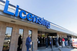People wait in line outside of the Lynnwood Department of Licensing before it opens on Friday, April 18, 2025 in Lynnwood, Washington. (Olivia Vanni / The Herald)
