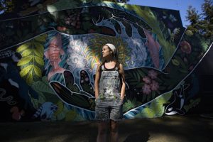 Local artist Gabrielle Abbott with her mural "Grateful Steward" at South Lynnwood Park on Wednesday, April 21, 2021 in Lynnwood, Wash. (Olivia Vanni / The Herald)
