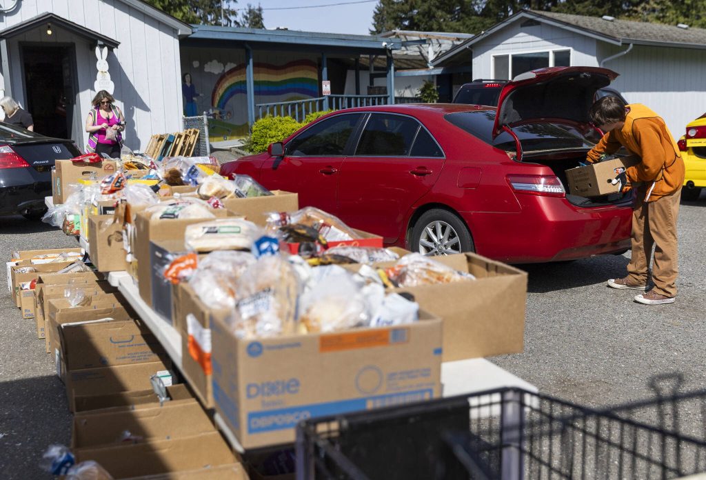 Tru Illes places a box of food in a trunk at the Faith Lutheran Food Bank on Friday, April 25, 2025 in Everett, Washington. (Olivia Vanni / The Herald)