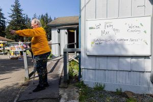 Founder of Faith Lutheran Food Bank Roxana Boroujerd helps direct car line traffic while standing next to a whiteboard alerting clients to their date of closing on Friday, April 25, 2025 in Everett, Washington. (Olivia Vanni / The Herald)