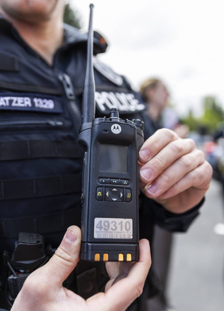 Everett Master Police Officer Travis Katzer shows one of the new police radios at a press conference outside of the new Snohomish County 911 building on Wednesday, April 30, 2025 in Everett, Washington. (Olivia Vanni / The Herald)