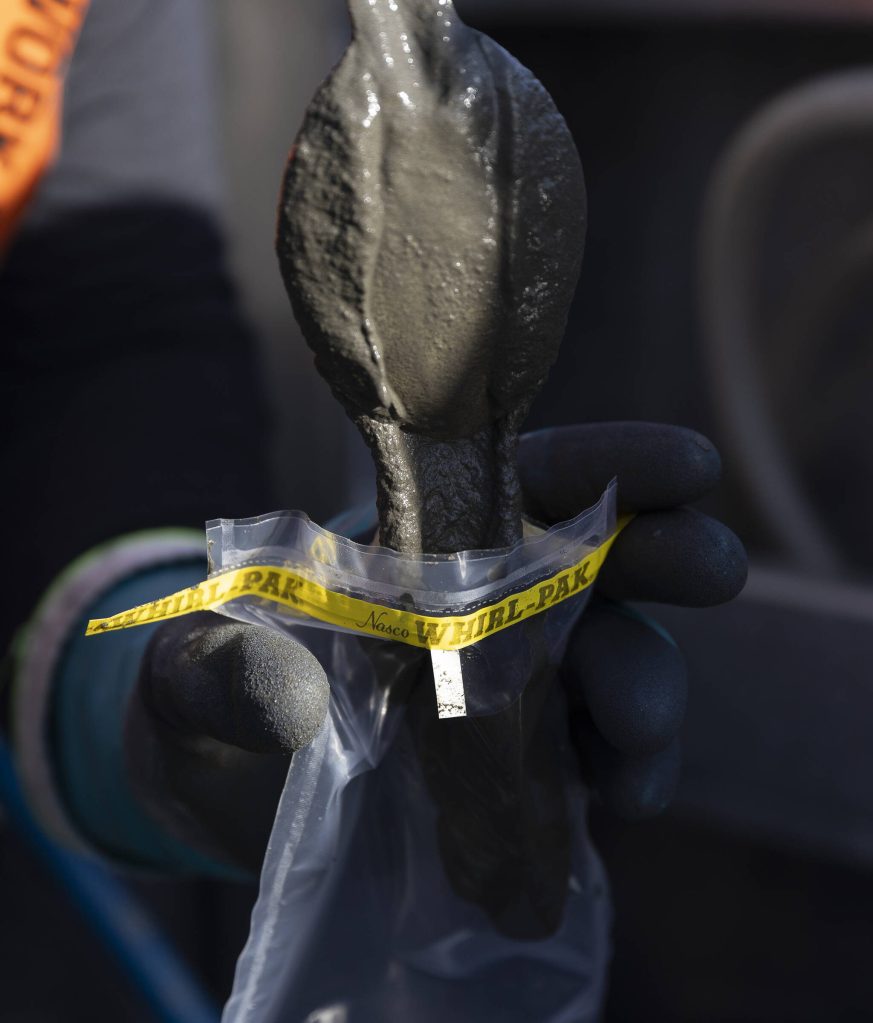 Chad Eshelman drops mixed sediment into a small bag to send off for testing on Thursday, May 1, 2025 in Everett, Washington. (Olivia Vanni / The Herald)