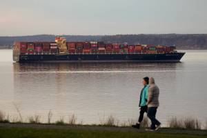 A couple walks around Harborview Park as the  Seaspan Brilliance, a 1,105-foot cargo ship, moors near the Port of Everett on Wednesday, Feb. 3, 2021 in Everett, Washington.  The ship is moored until it can offload its cargo in Vancouver, B.C. (Andy Bronson / The Herald)
