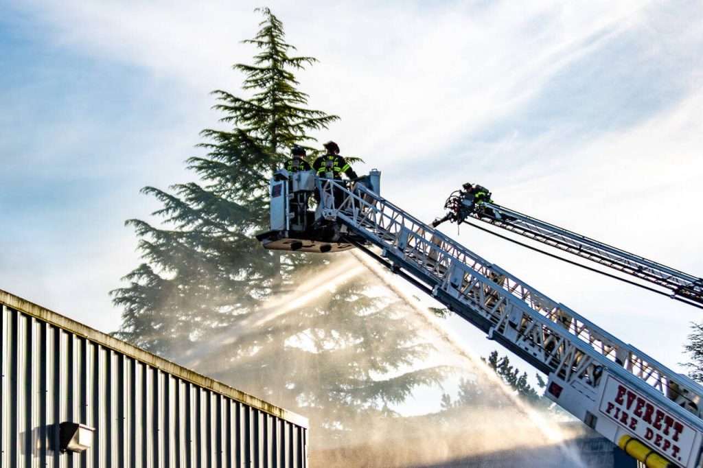 Firefighters spray water from a ladder truck onto Trojan Storage on Monday, May 5, 2025, in Everett, Washington. (Aaron Kennedy / The Herald)