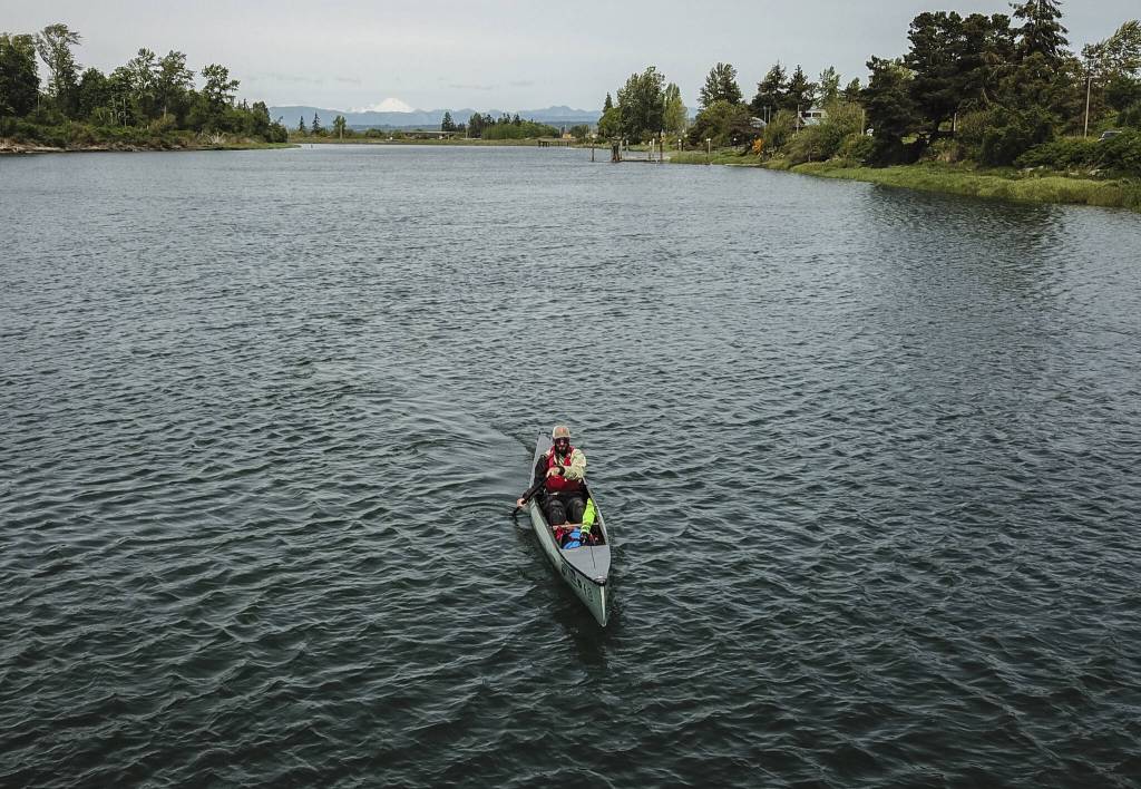 Kyle Parker paddles his canoe along the Snohomish River next to Langus Riverfront Park on Thursday, May 8, 2025 in Everett, Washington. (Olivia Vanni / The Herald)
