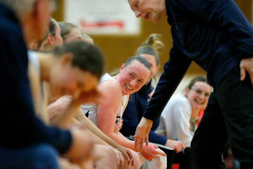 The Arlington bench all laugh as head coach Joe Marsh chooses five substitutes for his starters in the final minute of a win against Lynnwood on Tuesday, Feb. 14, 2023, at Marysville Pilchuck High School in Marysville, Washington. (Ryan Berry / The Herald)
