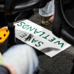 A “SAVE WETLANDS” poster is visible under an seat during a public hearing about Critical Area Regulations Update on ordinance 24-097 on Wednesday, May 14, 2025 in Everett, Washington. (Olivia Vanni / The Herald)