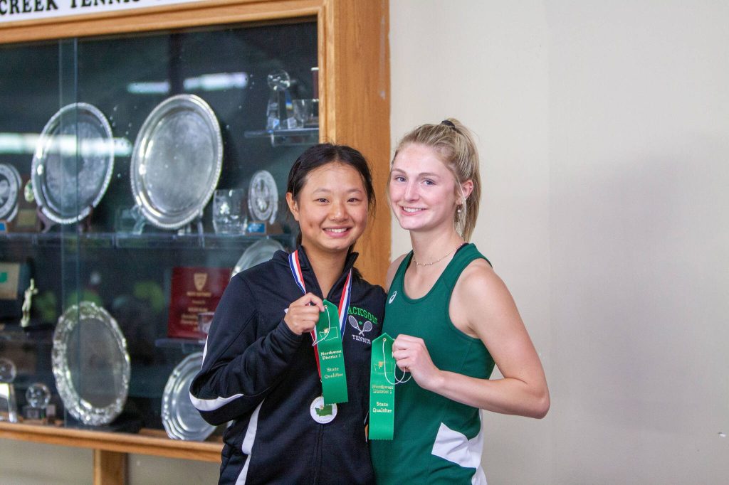 Jacksons Jasmine Wijaya (left) and Gracie Schouten (right) pose for a photo after their District 1 4A singles championship match on May 14, 2025 at Mill Creek Tennis Club. (Qasim Ali / The Herald)