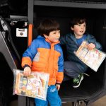 Theodore Lynch, 6, and Aarian Alchholz, 6, sit on the side of a Snohomish County Airport Fire Department fire engine during Paine Field Community Day on Saturday in Everett. (Will Geschke / The Herald)