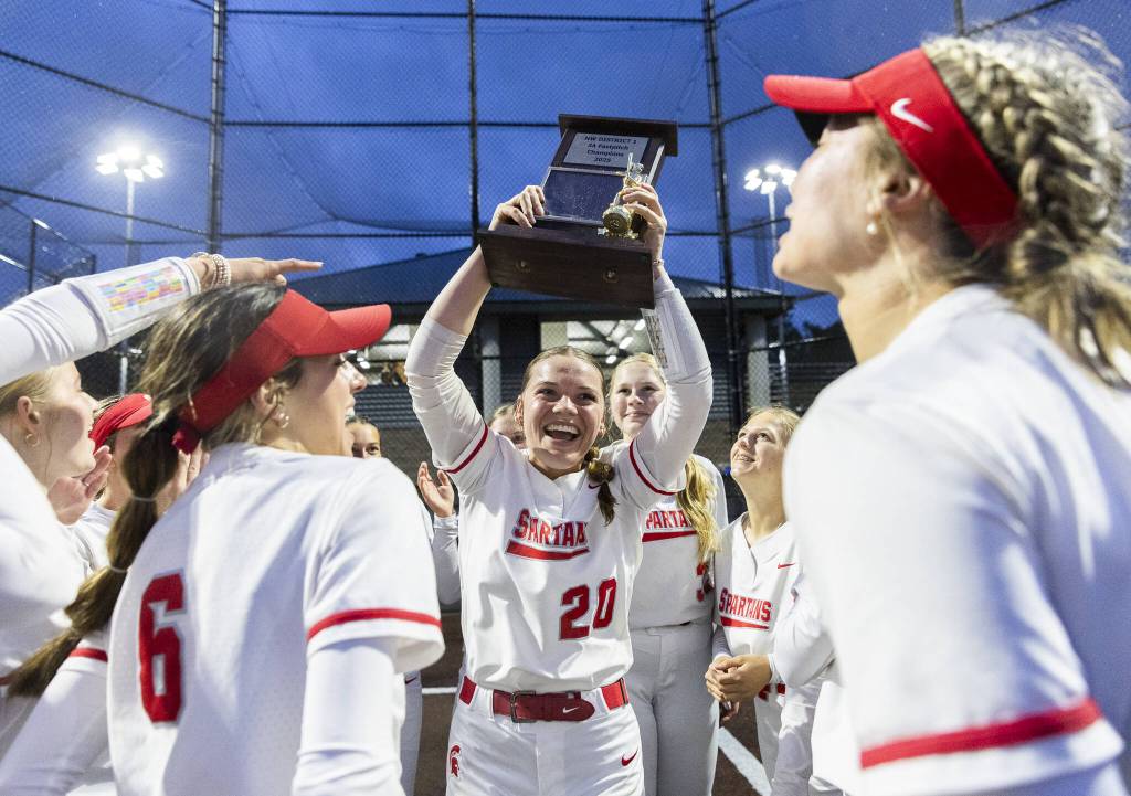 Stanwood players cheer as pitcher Addi Anderson lifts the 3A District 1 Championship trophy in the air after beating Sedro-Woolley for the title on Thursday, May 15, 2025 in Everett, Washington. (Olivia Vanni / The Herald)