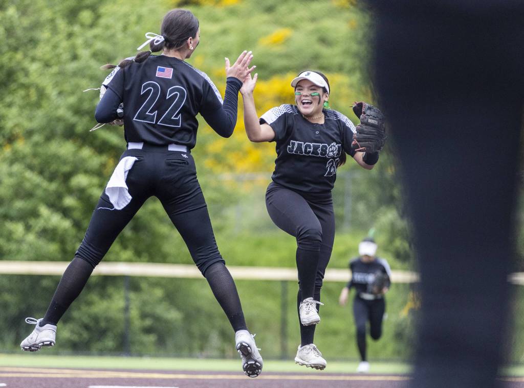 Jacksons Matea Lopez and Allie Thomsen leap in the air and high five during the 4A District 1 game against Lake Stevens on Friday, May 16, 2025 in Everett, Washington. (Olivia Vanni / The Herald)