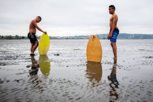 Ellis Johnson, 16, left, and brother Garrett Johnson, 13, take a breather after trying to find enough water to skim board on without sinking into the sand during opening day of Jetty Island on Friday, July 5, 2019 in Everett, Wash. (Olivia Vanni / The Herald)