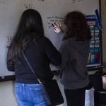 People pause to write messages on a classroom whiteboard on Thursday, May 29, 2025 in Marysville, Washington. (Olivia Vanni / The Herald)