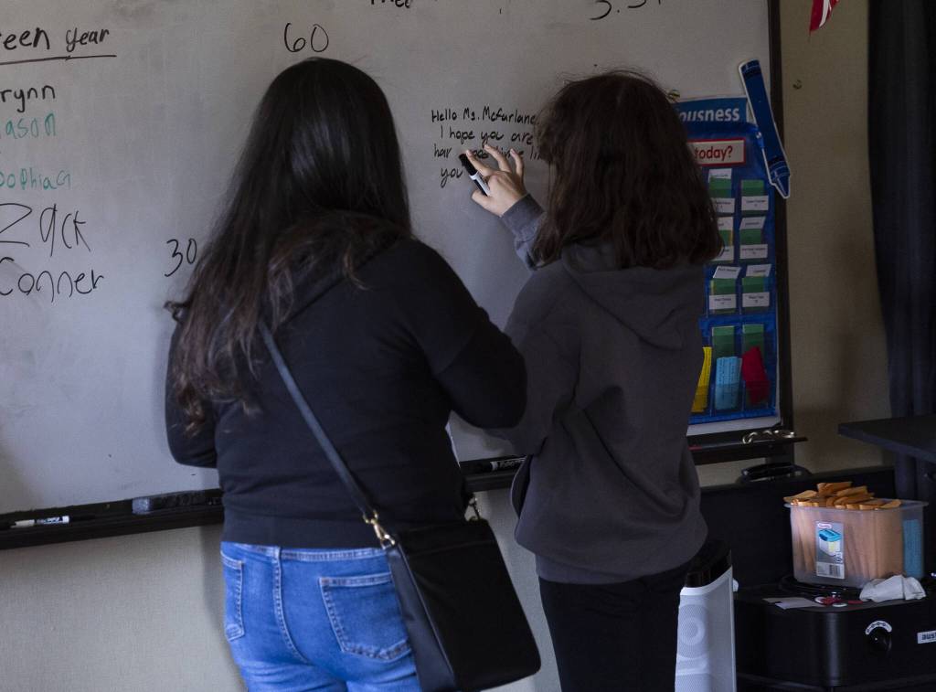 People pause to write messages on a classroom whiteboard on Thursday, May 29, 2025 in Marysville, Washington. (Olivia Vanni / The Herald)