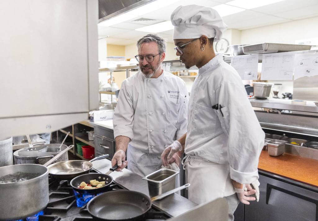 Chef Instructor Kevin Fogerty, left, shows Jahmarion Morey how to cook gnocchi in a pan at the Edmonds College Cafe on Thursday, May 29, 2025 in Lynnwood, Washington. (Olivia Vanni / The Herald)
