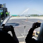People take photos and videos as the first Frontier Arlines flight arrives at Paine Field Airport under a water cannon salute on Monday, June 2, 2025 in Everett, Washington. (Olivia Vanni / The Herald)