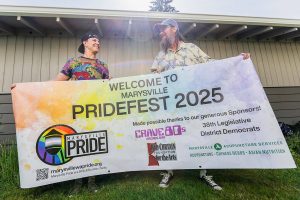 Marysville Pride organizers Vee Gilman, left, and Mike Pieckiel hold their welcome banner on Thursday, June 5, 2025 in Marysville, Washington. (Olivia Vanni / The Herald)