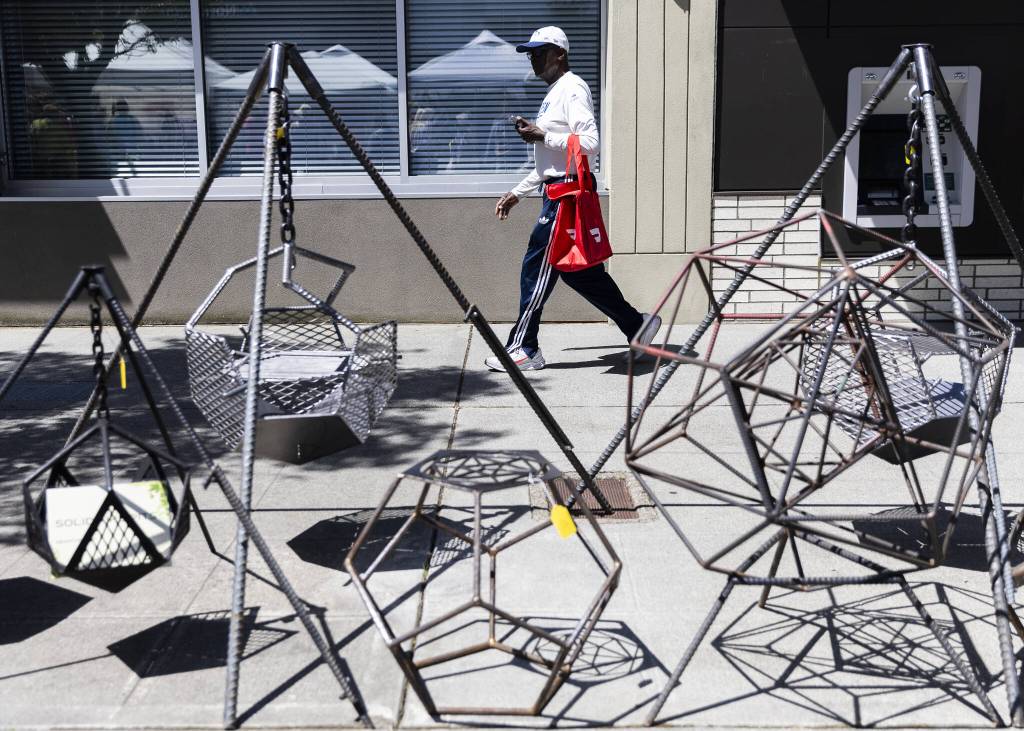 People walk past a selection of metalwork during Sorticulture on Friday, June 6, 2025 in Everett, Washington. (Olivia Vanni / The Herald)