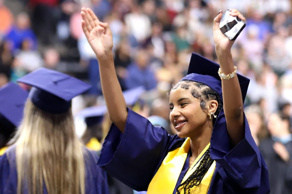 A graduate acknowledges supporters in the stands during Everett High School's 2025 commencement on Saturday, June 14, 2025, at Angel of the Winds Arena in Everett, Washington. (Mike Henneke / The Herald)