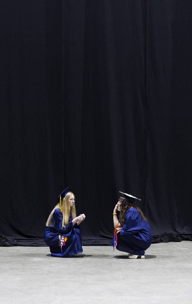 Graduates sit and talk backstage before the start of Mariner High Schools 2025 commencement on Friday, June 13, 2025, at Angel of the Winds Arena in Everett, Washington. (Olivia Vanni / The Herald)
