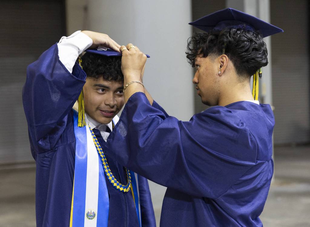 Neri Najera, right, helps Oswaldo Aquirre secure his graduation cap before the start of Mariner High Schools 2025 commencement on Friday, June 13, 2025, at Angel of the Winds Arena in Everett, Washington. (Olivia Vanni / The Herald)