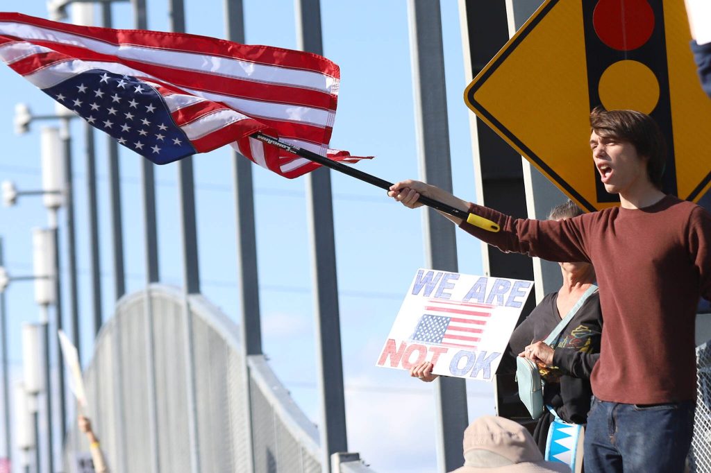 Josiah Morgan, of Snohomish, holds an upside down American flag during a No Kings Day rally along Broadway on Saturday in Everett. (Mike Henneke / The Herald)