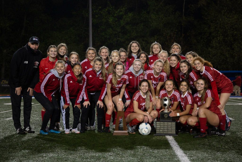 Wildcats coach Mike Bartley (furthest left) and the Archbishop Murphy girls soccer team celebrate a 2A state championship on November 20, 2021 at Shoreline Stadium. (Courtesy of Archbishop Murphy Athletics / Matt Todd)