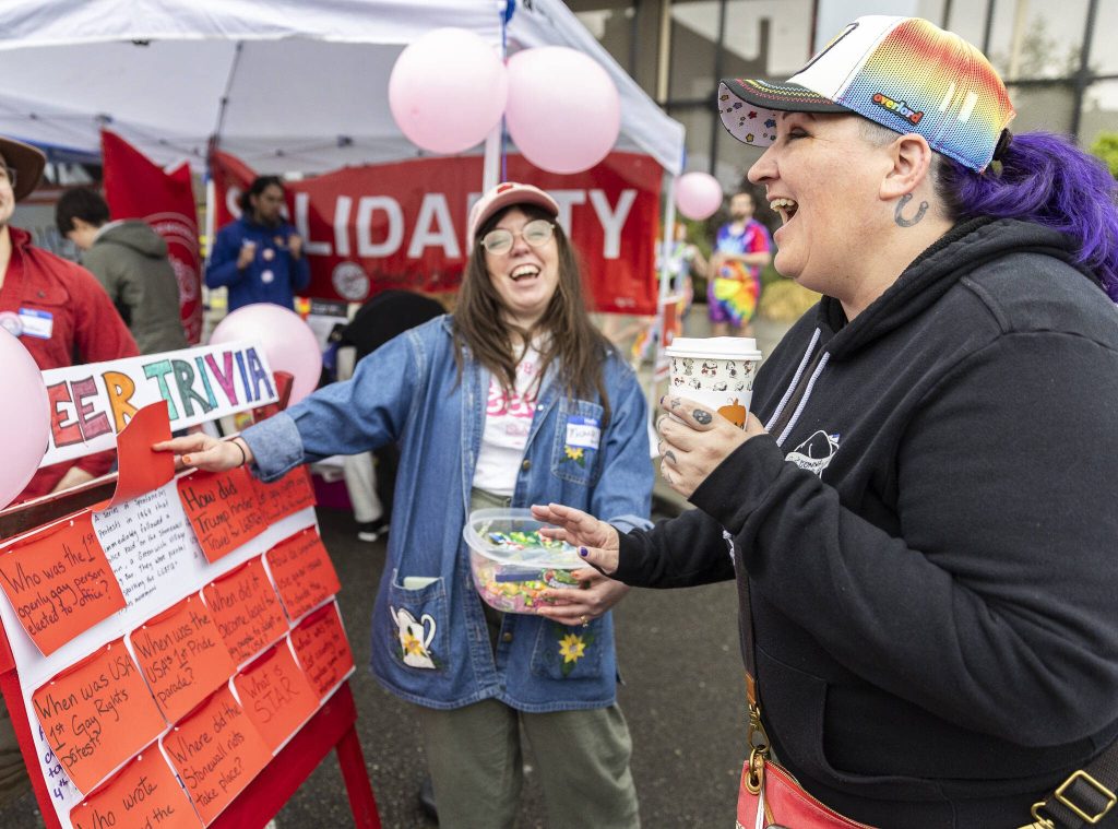 Dana McGlocklin, right, laughs after getting a queer trivia question correct during the Everett Pride Block Party on Saturday, June 21, 2025 in Everett, Washington. (Olivia Vanni / The Herald)