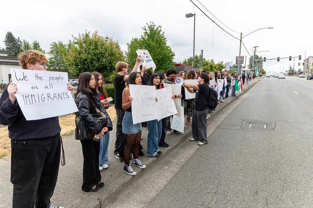 A group of Cascade High School students held signs and flags while protesting along Evergreen Way on Friday, June 20, 2025 in Everett, Washington. (Aaron Kennedy / The Herald)