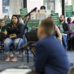 People hold up signs in protest while Everett Community Colleges Vice President of Human Resources Josh Ernst speaks on Thursday, June 26, 2025 in Everett, Washington. (Olivia Vanni / The Herald)
