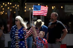 A young child holds up an American Flag during Everett’s Fourth of July Parade on Thursday, July 4, 2024, in downtown Everett, Washington. (Ryan Berry / The Herald)