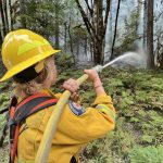 A firefighter with Sky Valley Fire sprays water on a hotspot Wednesday, Sept. 14, 2022, along U.S. 2 as the Bolt Creek fire continued to burn between Index and Skykomish. (Peter Mongillo / Snohomish Regional Fire and Rescue)