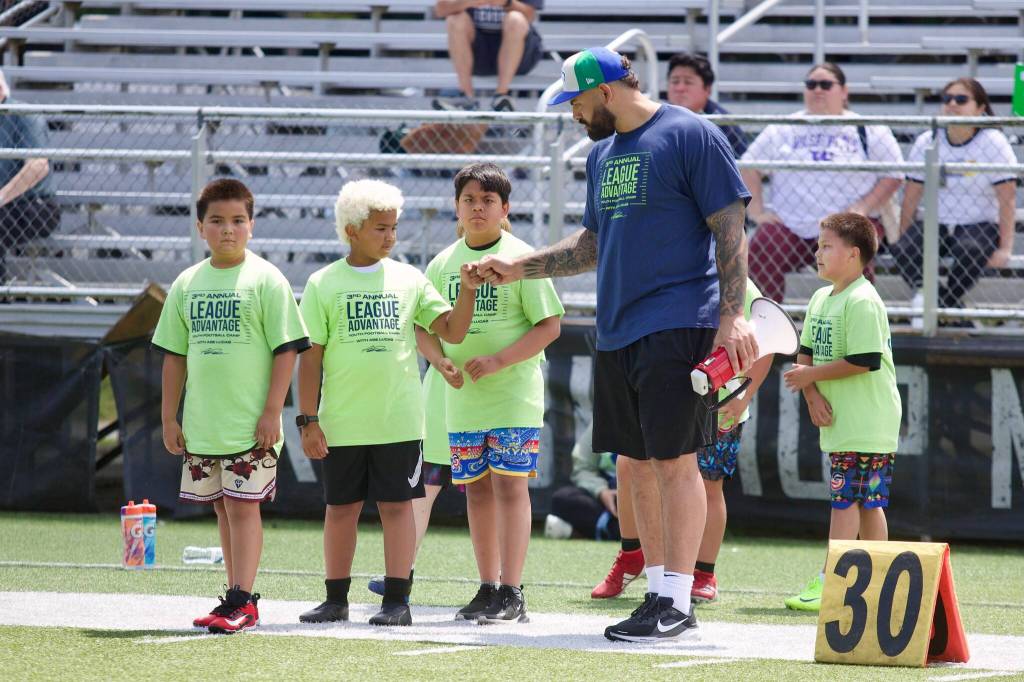 Seattle Seahawks offensive tackle Abraham Lucas fist bumps a camper at the third annual League Advantage Youth Football Camp at Lucas alma mater, Archbishop Murphy High School, in Everett, Washington on Saturday, June 28, 2025. (Joe Pohoryles / The Herald)