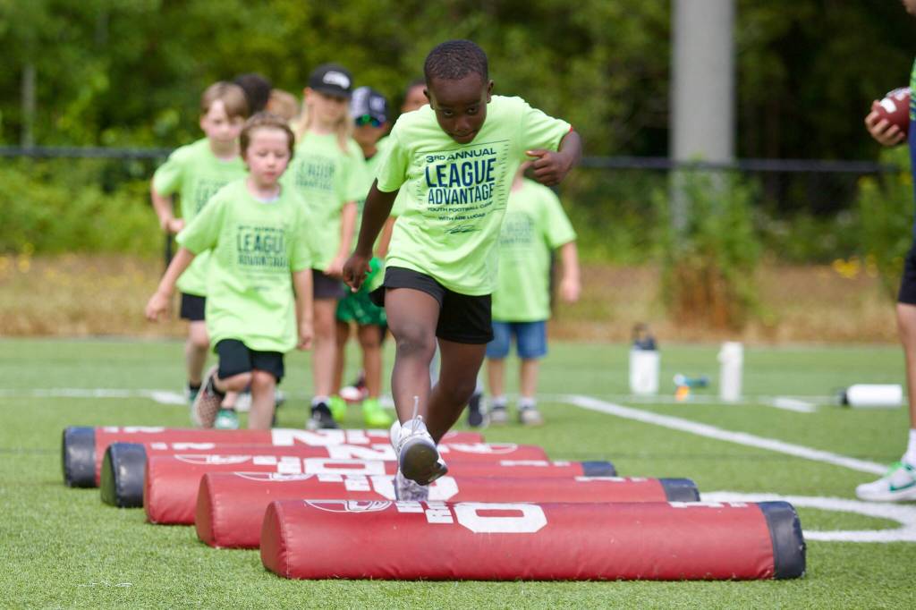 A group of younger campers run through a stepover pad drill at the third annual League Advantage Youth Football Camp at Archbishop Murphy High School, in Everett, Washington on Saturday, June 28, 2025. (Joe Pohoryles / The Herald)