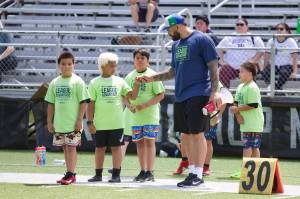 Seattle Seahawks offensive tackle Abraham Lucas fist bumps a camper at the third annual League Advantage Youth Football Camp at Lucas' alma mater, Archbishop Murphy High School, on Saturday, June 28, 2025. (Joe Pohoryles / The Herald)